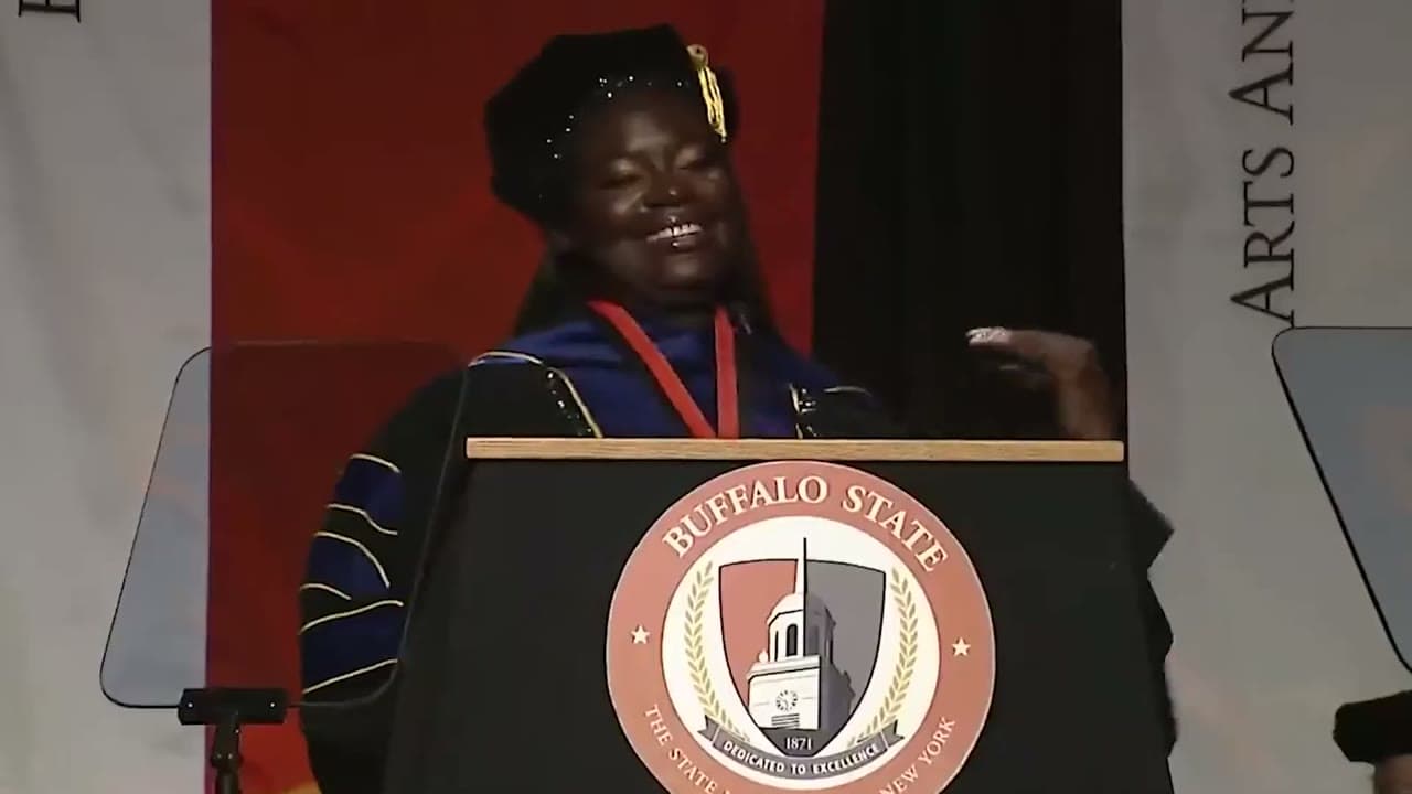 Dr. Raven Baxter laughing at the Buffalo State commencement podium