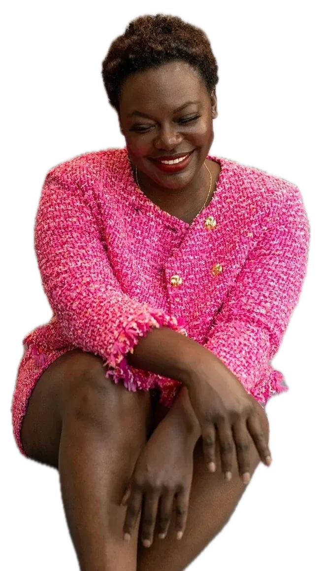Dr. Raven Baxter smiling, seated, in a pink tweed suit